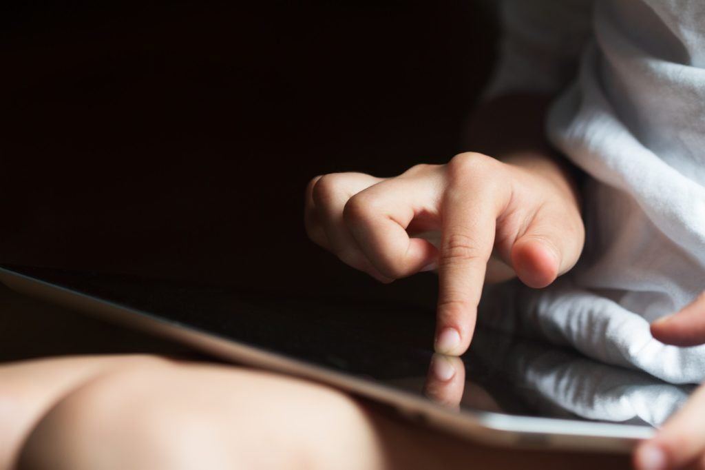 child hand touching the screen of a tablet