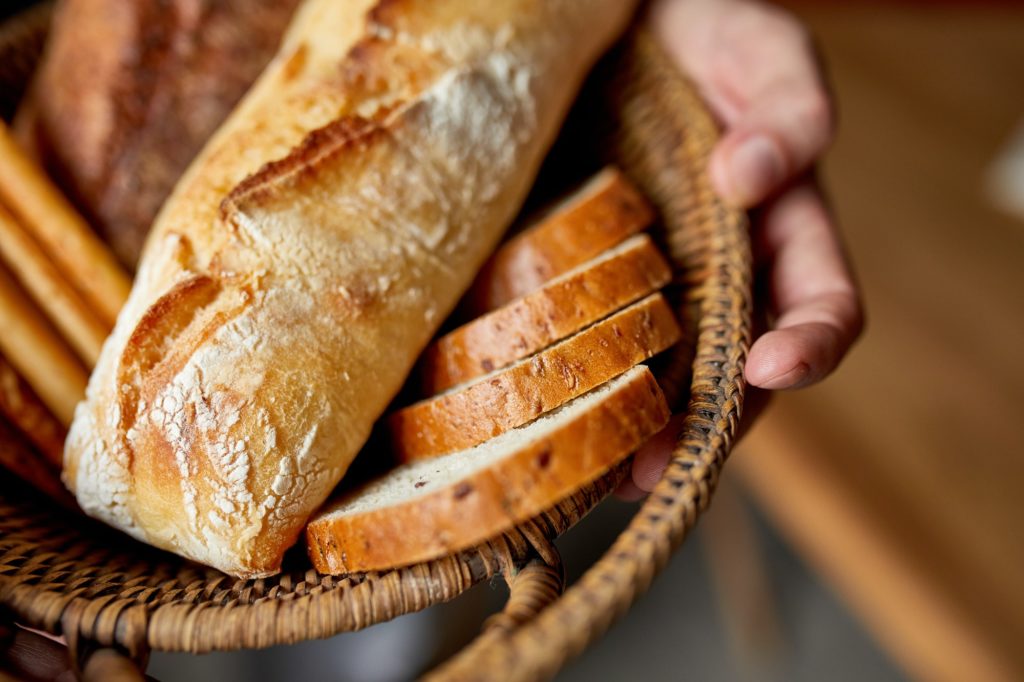 Close yp of man hand, holding basket with various bread freshly baked.