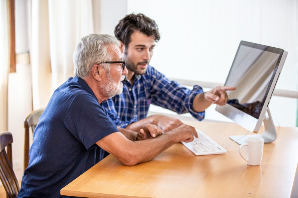 man teaching elderly man to using computer