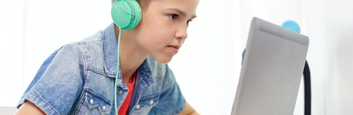 boy in headphones playing video game on laptop